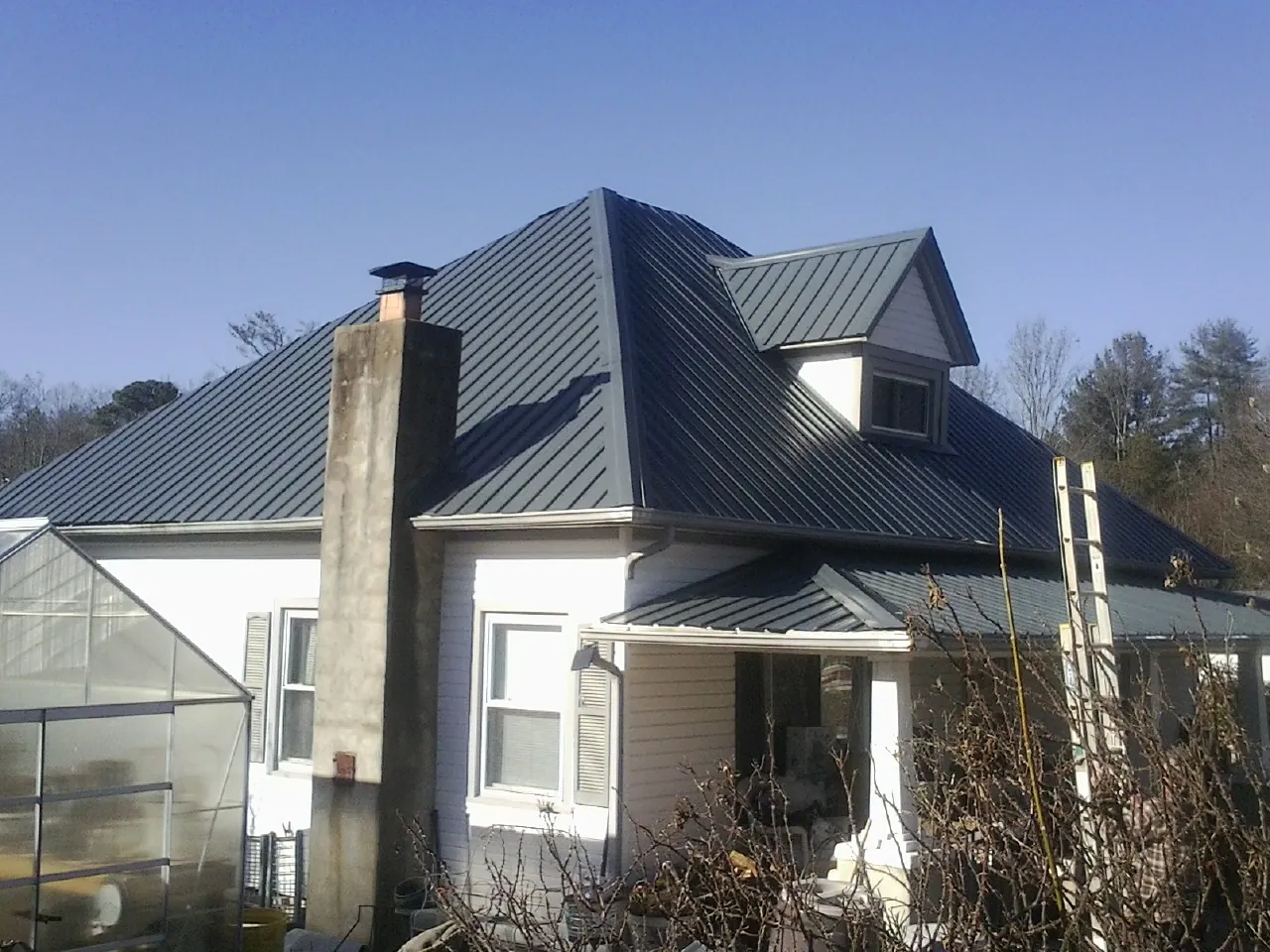 Dark blue standing seam metal roof on a white farmhouse with dormer — Slate & Tile Roof Repair by Roofing Brothers in Diablo
