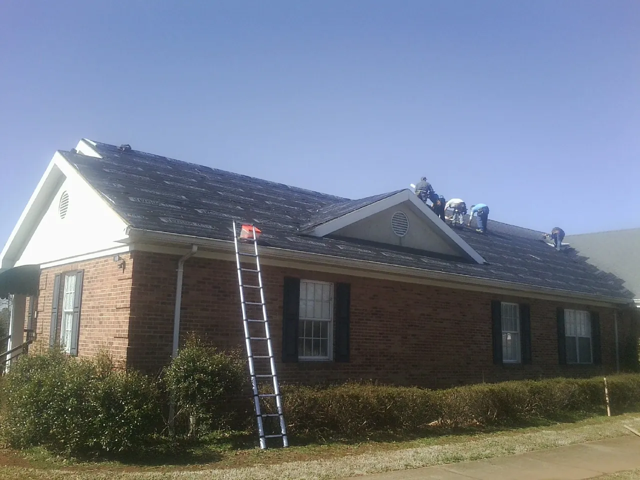 Crew tearing shingles off a brick ranch roof with a ladder set — Metal Roof Repair work by our crew in Diablo