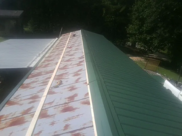 Old rusted panels beside newly installed green metal roofing — Wind Damage Roof Repair by Roofing Brothers in Diablo