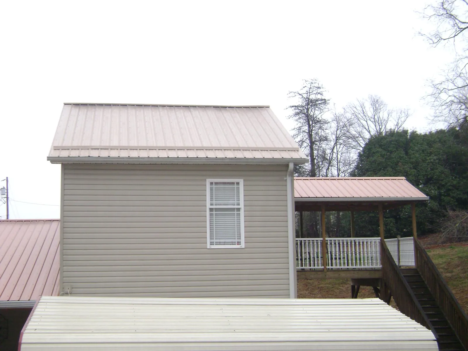 Tan metal roofs on a two story addition and attached porch, from a Roof Replacement job in Diablo