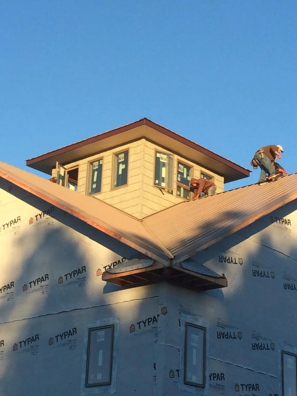 Roofers working around a rooftop cupola on a new metal roof at sunset — Roof Waterproofing in Diablo by Roofing Brothers